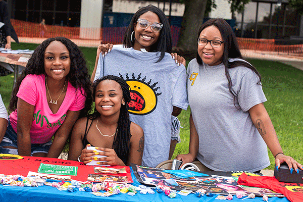 A group of African American students pose for a photo while sitting at a table during the annual Street Fair at the Charle Brown African American Cultural Center. 